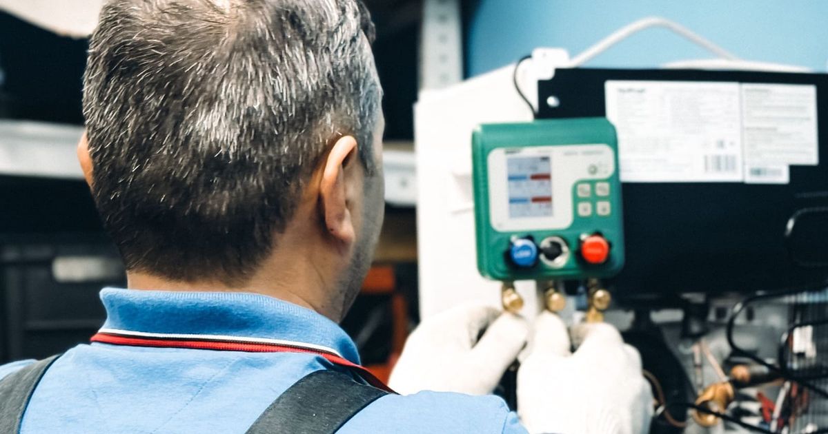 Technician checking pressure gauges while servicing an air conditioning unit