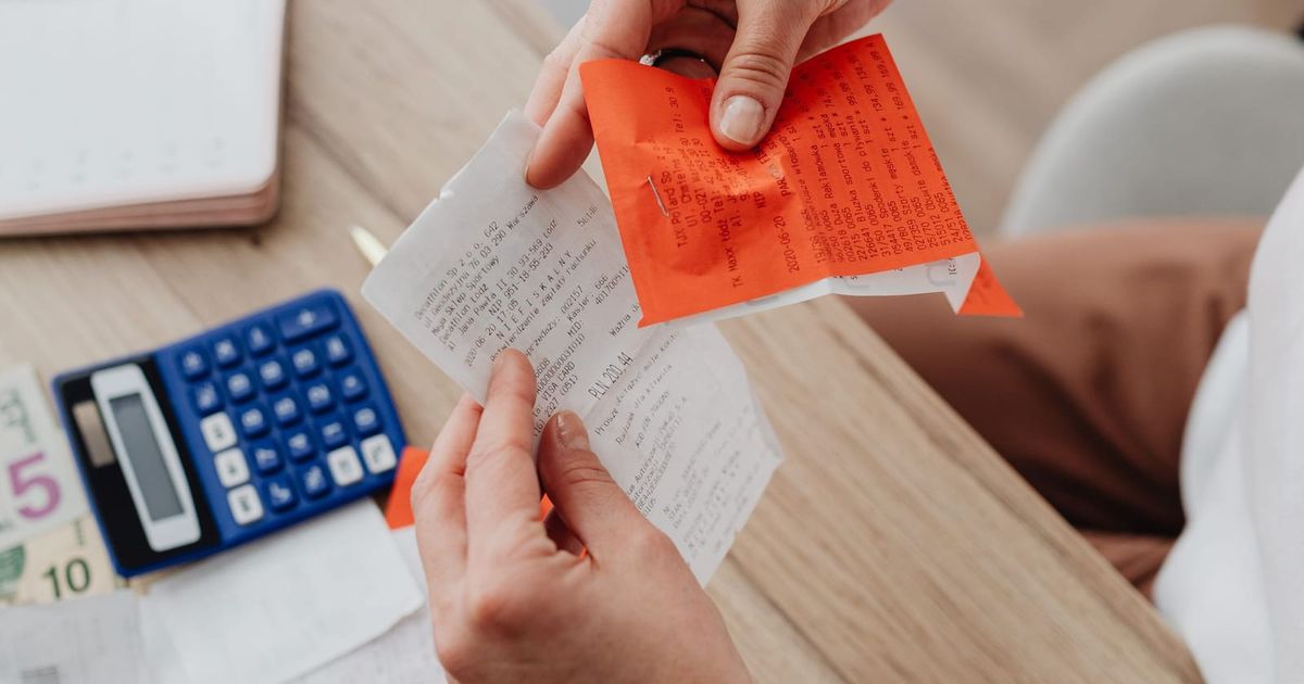Hands holding a receipt next to a calculator and notes