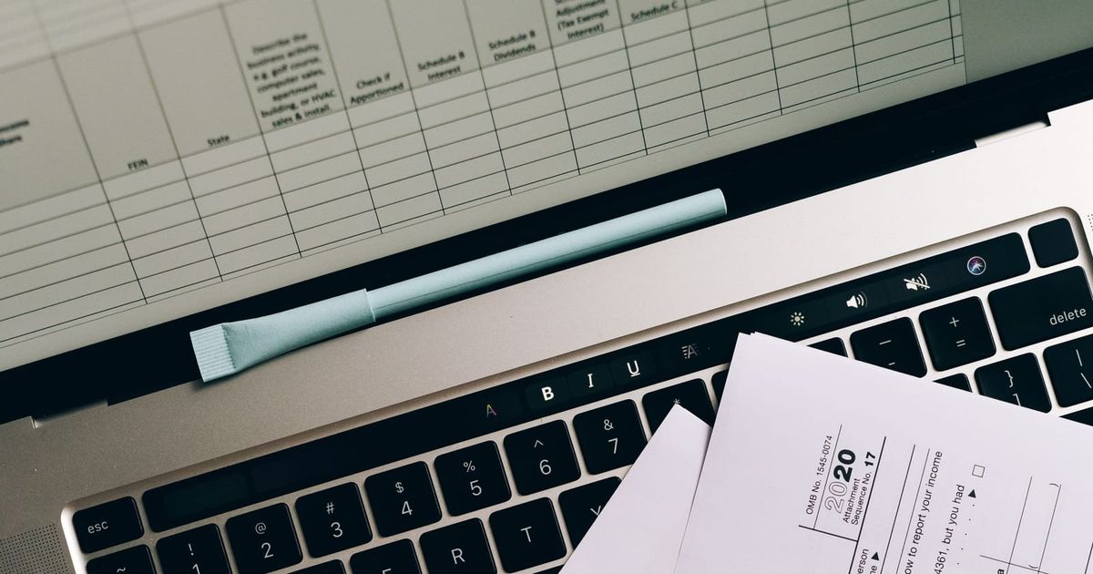 Laptop, phone calculator and small business accounting paperwork on a desk