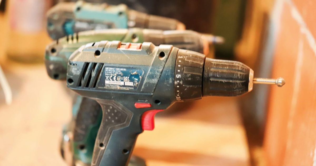 Row of cordless drills lined up on a timber workbench
