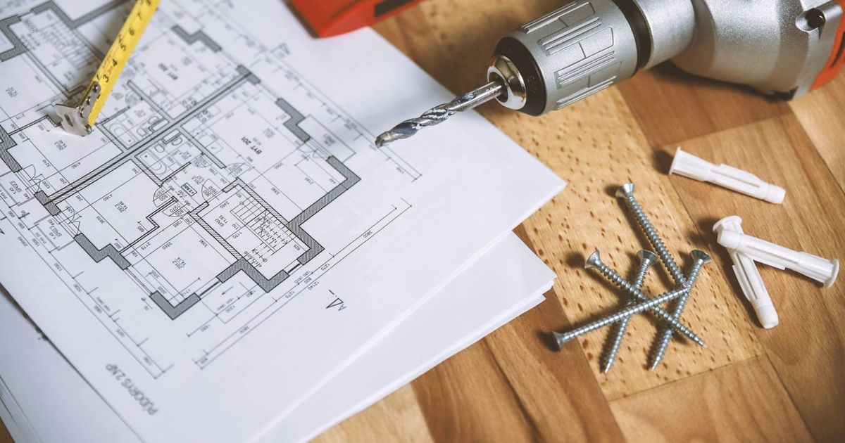 House floor plan on a timber table with a drill, screws and a spirit level