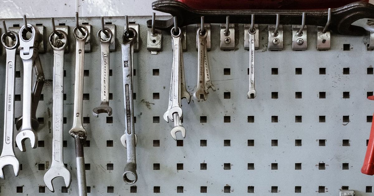 Spanners and hand tools hanging on a workshop pegboard