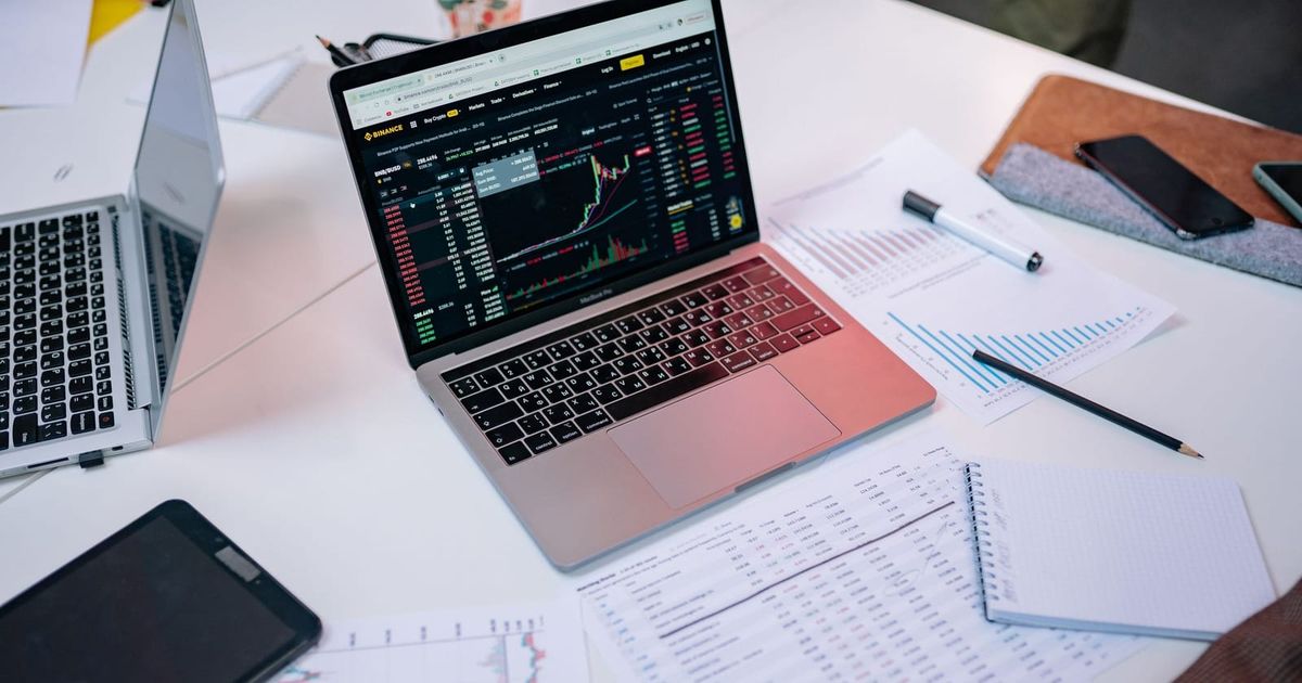 Laptops showing financial charts beside printed reports