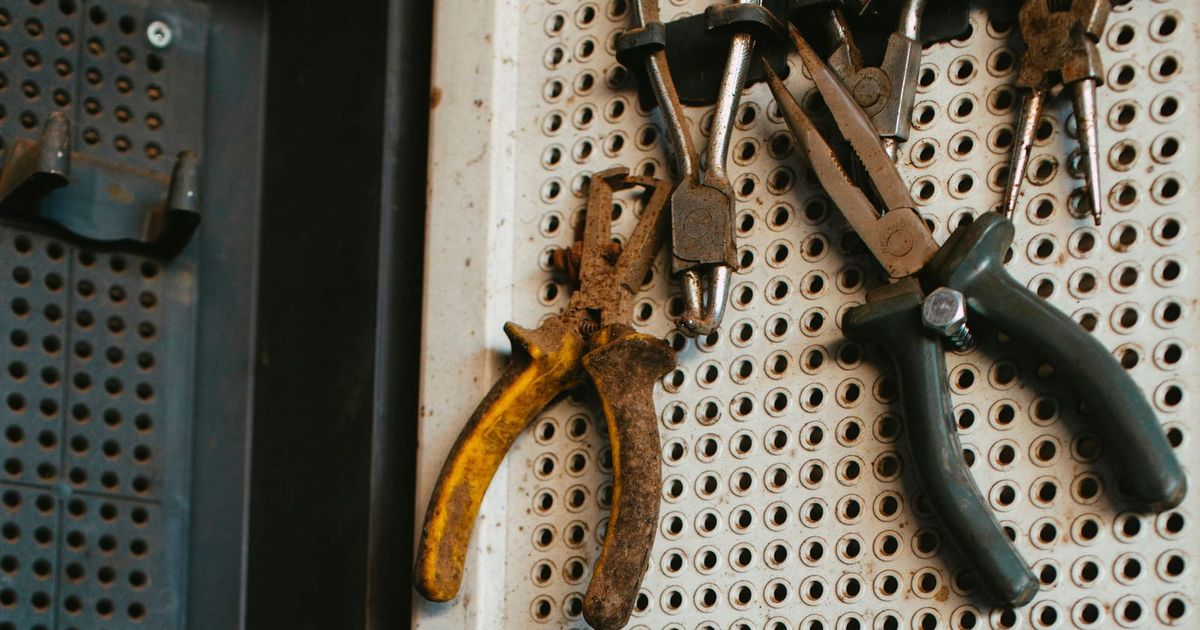 Pliers and hand tools hanging on a workshop pegboard