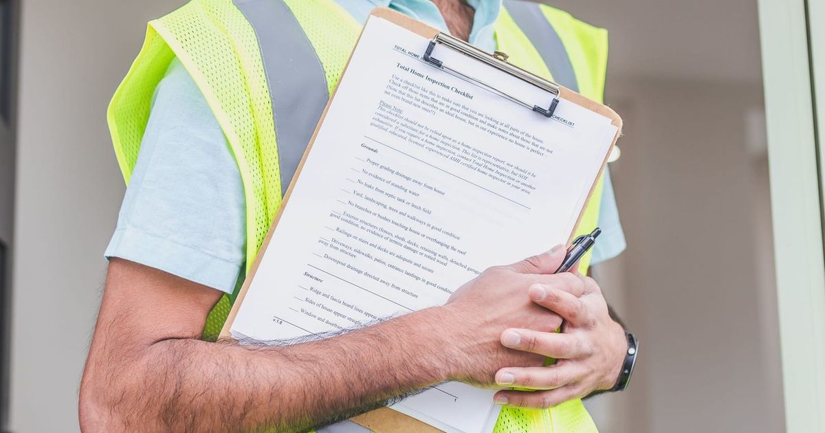 Worker in a hi-vis vest holding a clipboard with paperwork