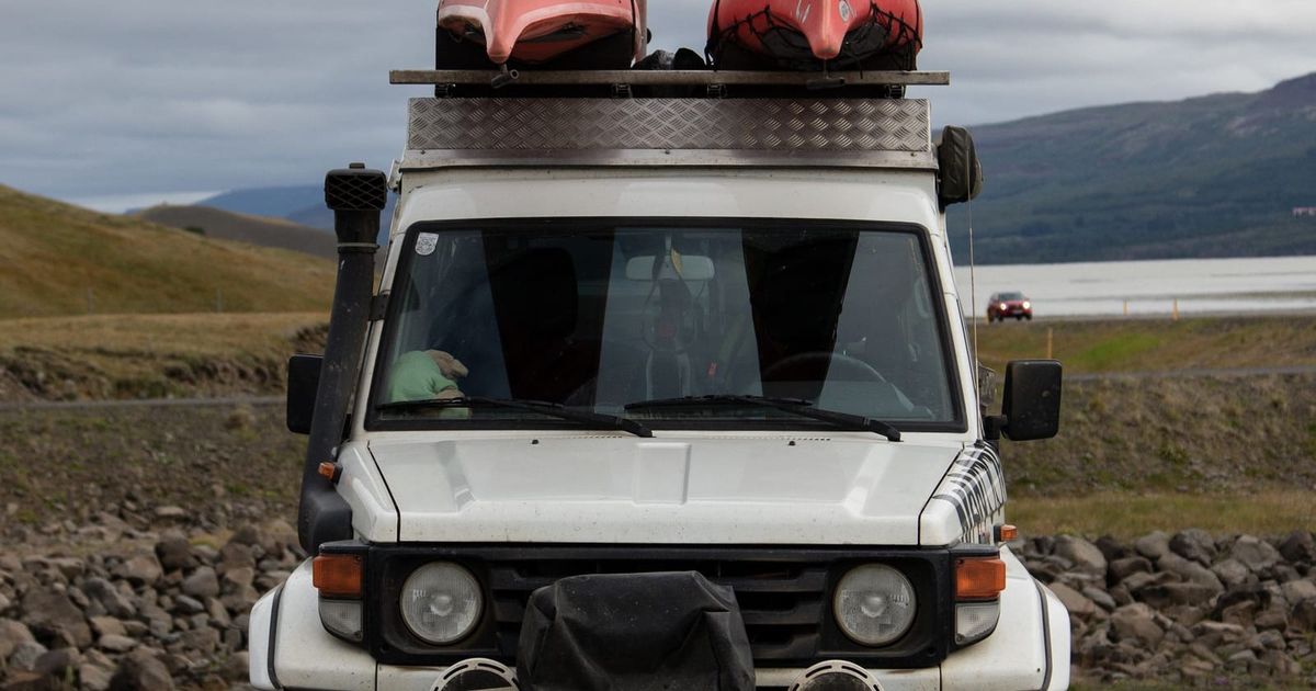 Four-wheel drive with a loaded roof rack parked on a rocky track